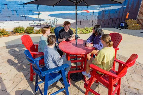 A group of students having a conversation at a table on the 勃兰特学生中心 patio